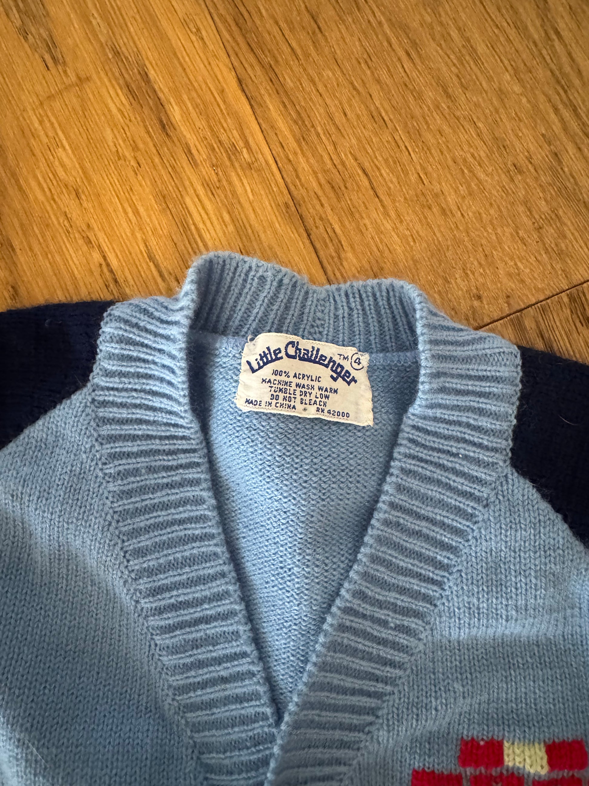 Close-up of a blue sweater with a brand label on a wooden surface